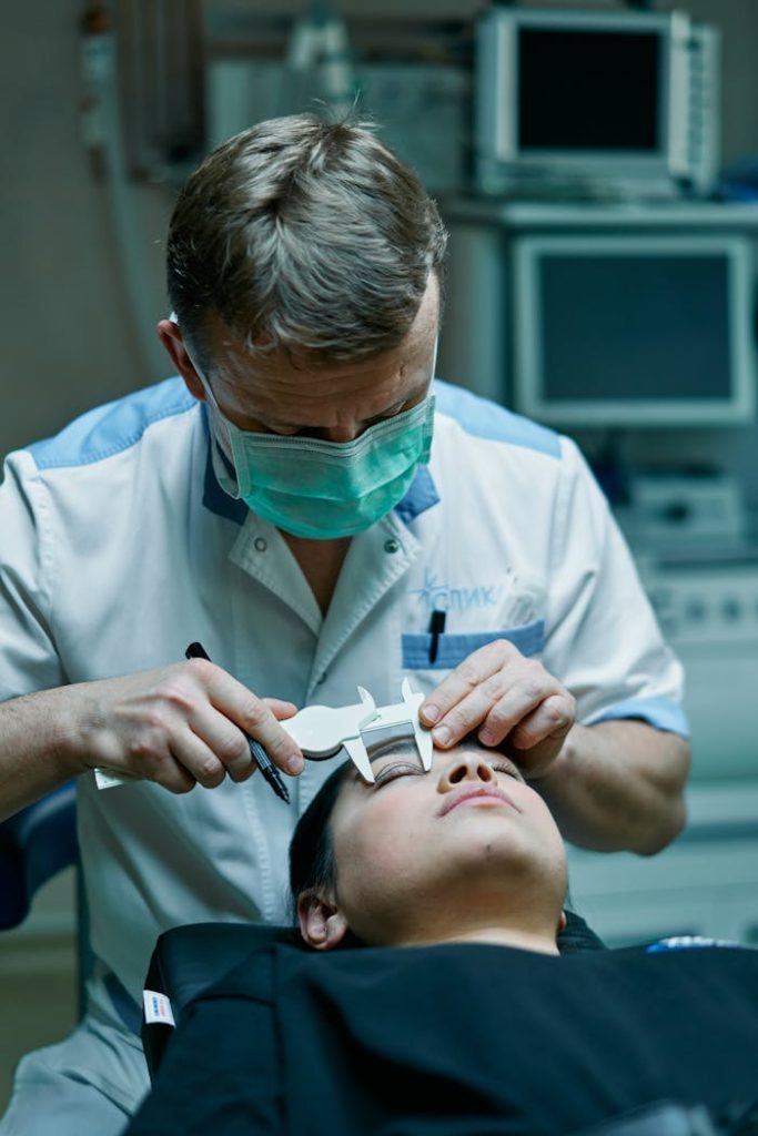 A surgeon measures a patients eyelids with calipers in a medical clinic, preparing for a procedure.